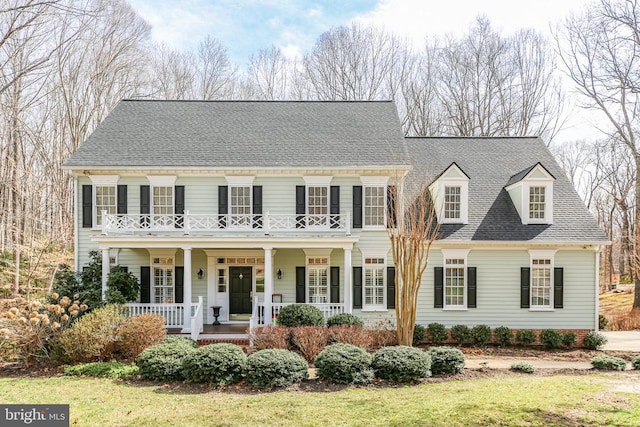 view of front of property featuring a balcony, covered porch, and a shingled roof