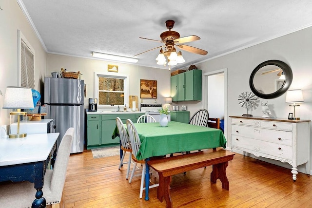 dining room with light wood finished floors, ceiling fan, and ornamental molding