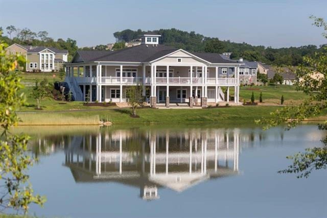 back of property featuring a deck with water view and a yard