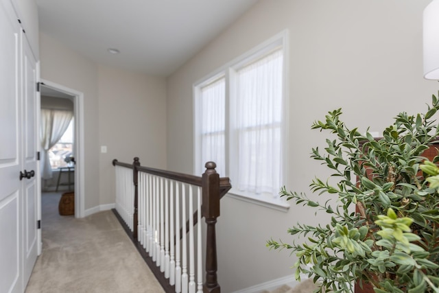 corridor with baseboards, light carpet, and an upstairs landing