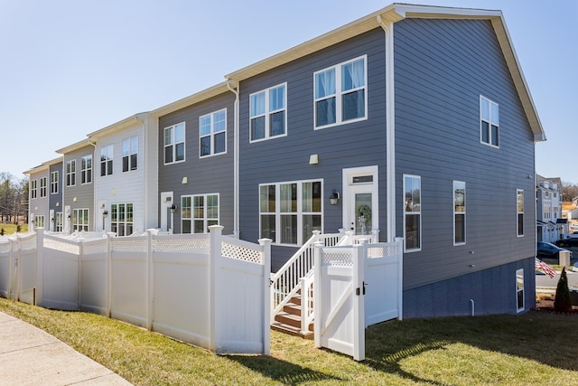 rear view of house featuring a yard and fence