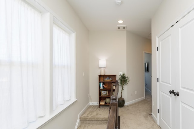 corridor with light carpet, visible vents, and baseboards