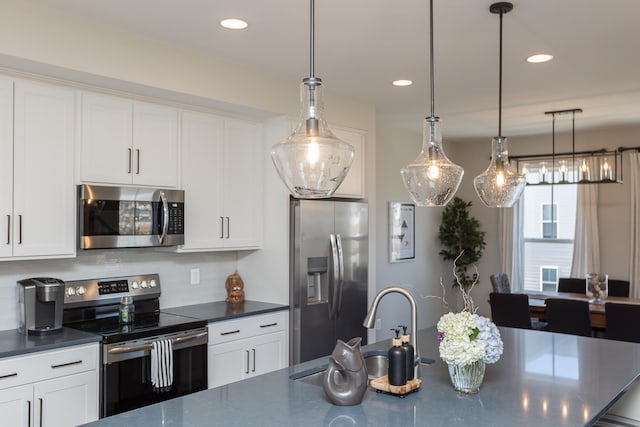 kitchen featuring a sink, stainless steel appliances, dark countertops, and white cabinetry