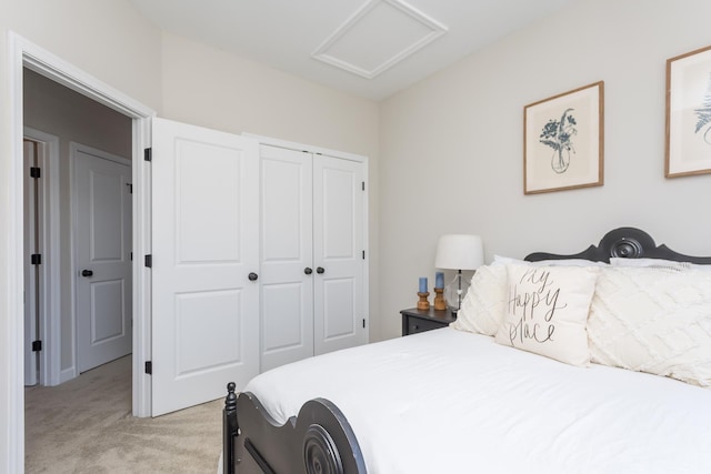 bedroom featuring a closet, light colored carpet, and attic access
