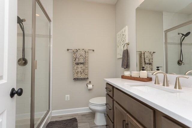 full bath featuring vanity, toilet, baseboards, and a stall shower