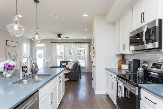 kitchen with tasteful backsplash, open floor plan, appliances with stainless steel finishes, dark wood-style floors, and a sink