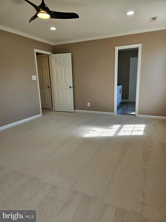 unfurnished bedroom with visible vents, baseboards, and ornamental molding