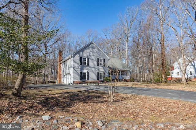 view of front of home featuring driveway, a chimney, and an attached garage