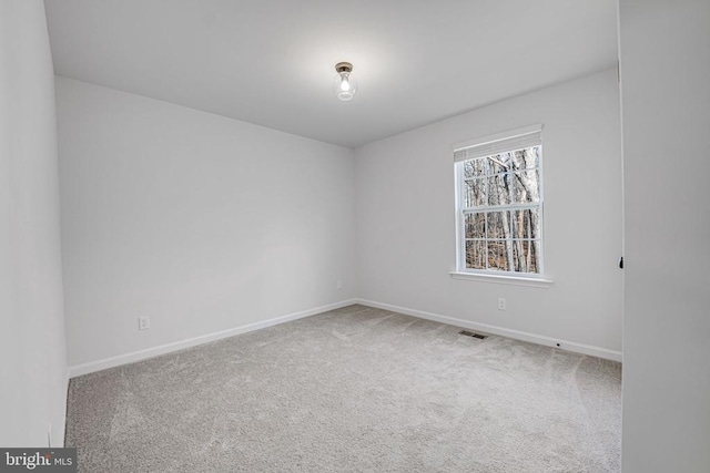 carpeted spare room with visible vents and baseboards