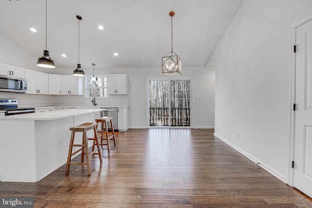 kitchen featuring lofted ceiling, a breakfast bar area, white cabinets, and appliances with stainless steel finishes