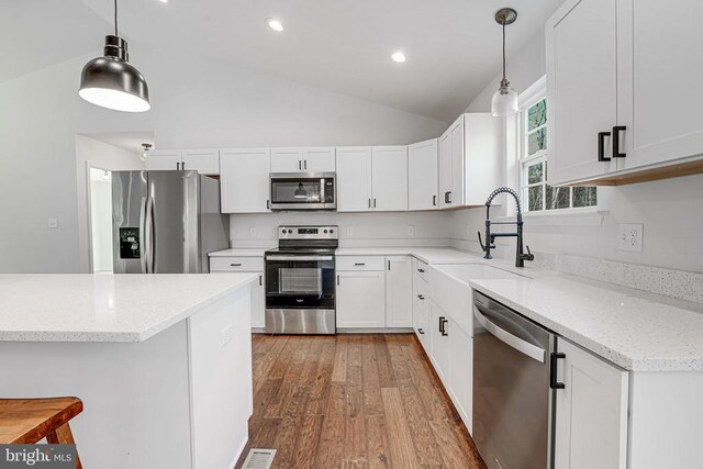 kitchen featuring pendant lighting, sink, white cabinetry, stainless steel appliances, and light stone countertops