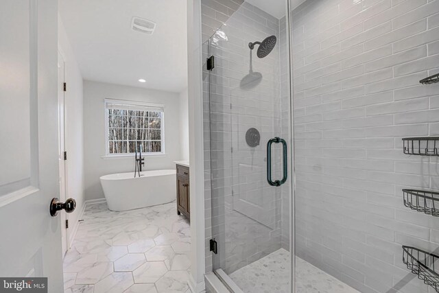 bathroom featuring a stall shower, visible vents, marble finish floor, a freestanding bath, and vanity