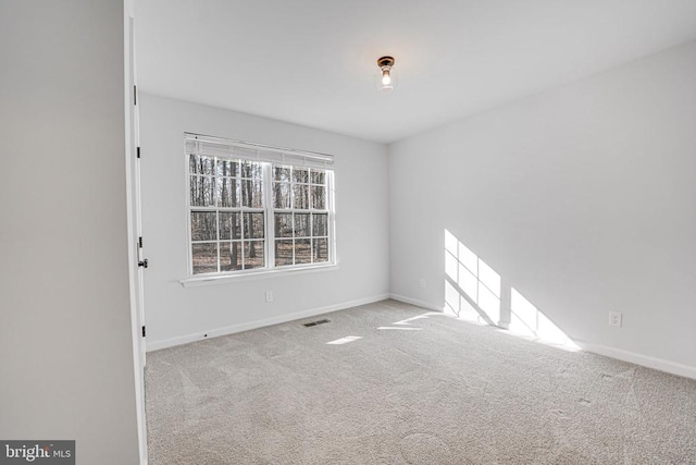 empty room featuring light carpet, visible vents, and baseboards