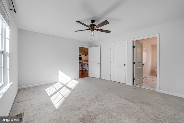 unfurnished bedroom featuring light colored carpet and connected bathroom