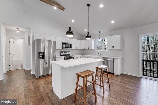 kitchen with white cabinets, appliances with stainless steel finishes, a center island, light countertops, and a sink