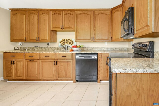 kitchen with light tile patterned floors, light stone countertops, sink, and black appliances