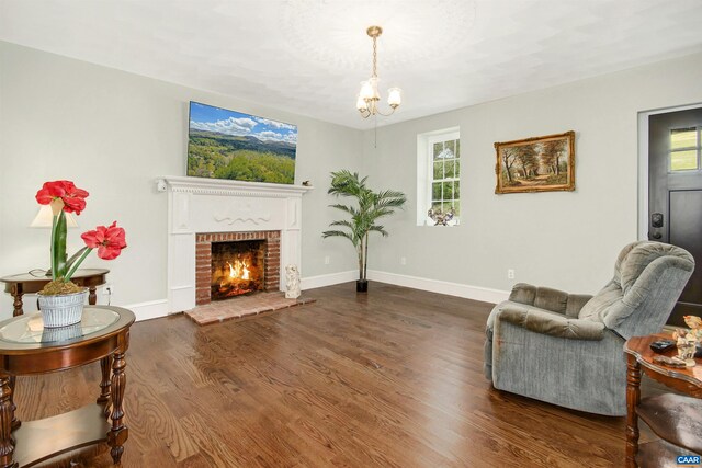 living room featuring a notable chandelier, dark hardwood / wood-style floors, a brick fireplace, and a wealth of natural light