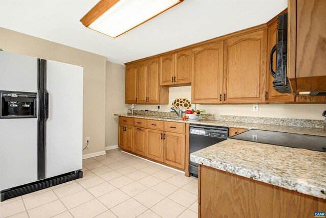 kitchen with light tile patterned flooring, sink, light stone counters, and black appliances