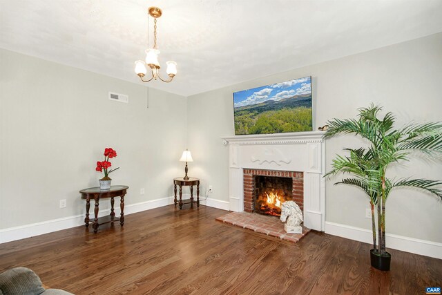 living room featuring an inviting chandelier, a fireplace, and dark hardwood / wood-style flooring