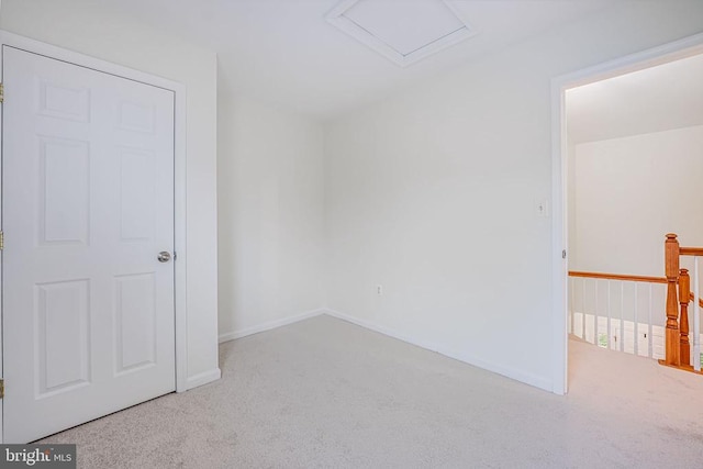 spare room with carpet flooring, attic access, and baseboards