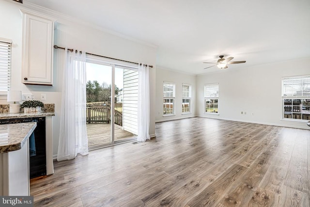 unfurnished living room featuring light wood-style floors, ornamental molding, and a wealth of natural light