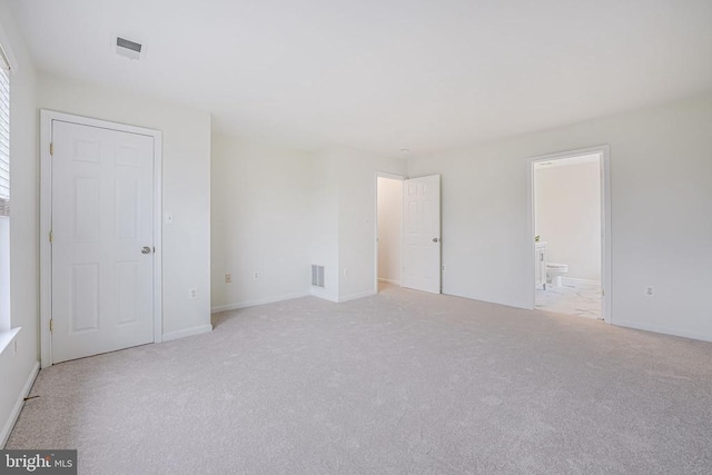 unfurnished bedroom with ensuite bath, visible vents, baseboards, and light colored carpet