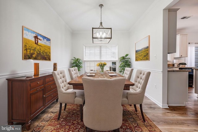 dining area with crown molding, visible vents, an inviting chandelier, wood finished floors, and baseboards