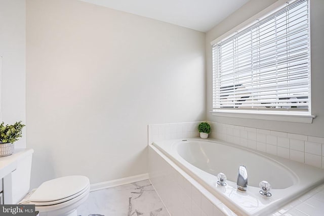 bathroom featuring toilet, marble finish floor, baseboards, and a bath