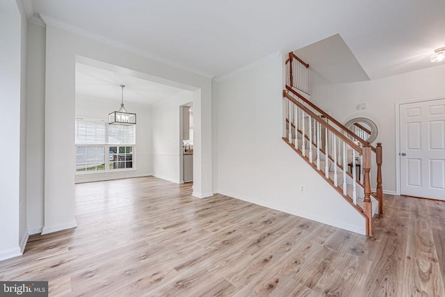 living area with a chandelier, baseboards, light wood finished floors, and stairs