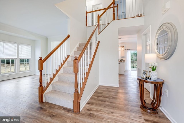 stairs featuring a high ceiling, baseboards, and wood finished floors