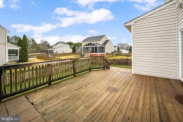 wooden terrace with a sunroom, a fenced backyard, and a residential view