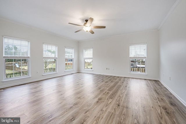 empty room featuring a healthy amount of sunlight, baseboards, ornamental molding, and wood finished floors