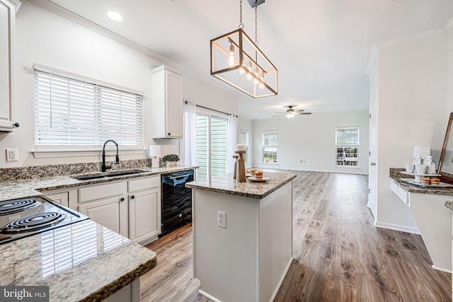 kitchen with crown molding, beverage cooler, a sink, and light wood finished floors