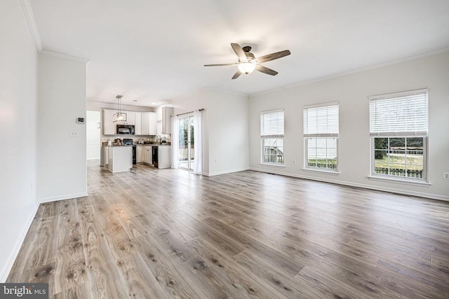 unfurnished living room with ceiling fan, a healthy amount of sunlight, light wood-style flooring, and crown molding