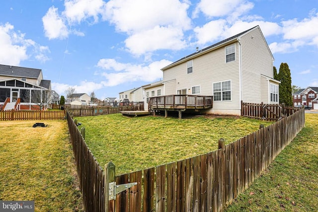 rear view of property with a deck, a fenced backyard, a sunroom, a yard, and a residential view