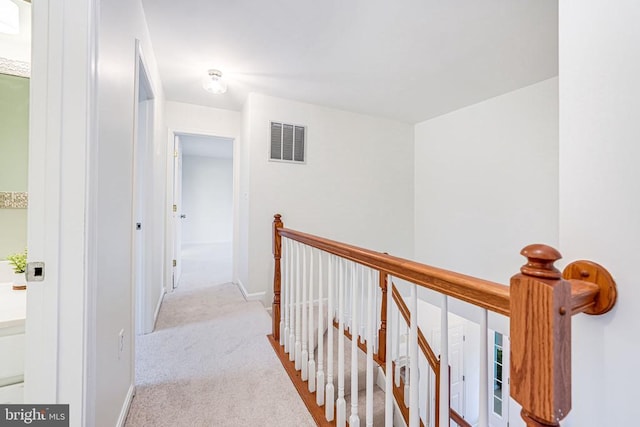 hallway featuring carpet flooring, an upstairs landing, visible vents, and baseboards