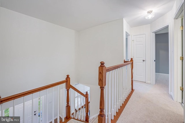 hall with light carpet, baseboards, and an upstairs landing