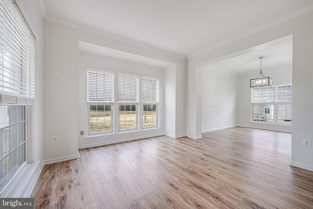 unfurnished living room with a chandelier, ornamental molding, wood finished floors, and a wealth of natural light