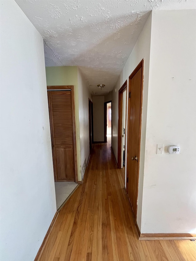 hallway with a textured ceiling and light wood-type flooring