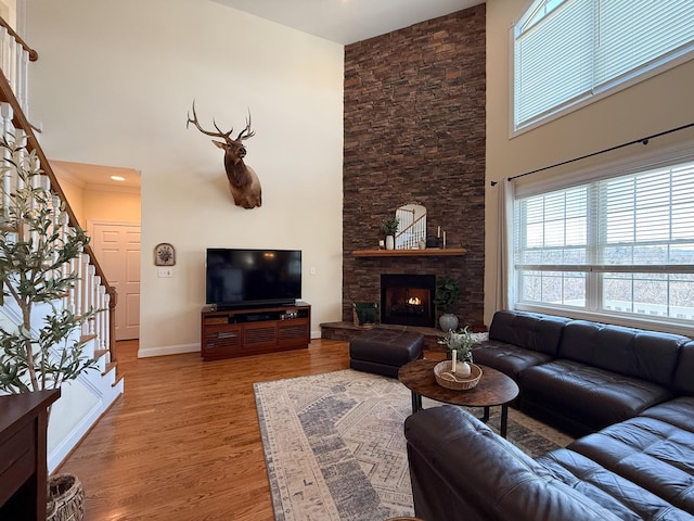 living area with stairs, a high ceiling, a fireplace, and wood finished floors