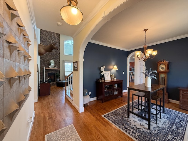 dining area featuring arched walkways, ornamental molding, stairway, and wood finished floors