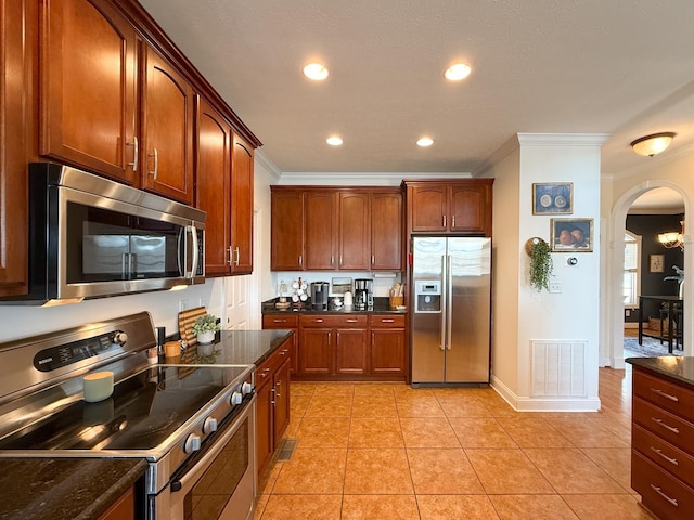 kitchen with arched walkways, crown molding, light tile patterned floors, visible vents, and appliances with stainless steel finishes