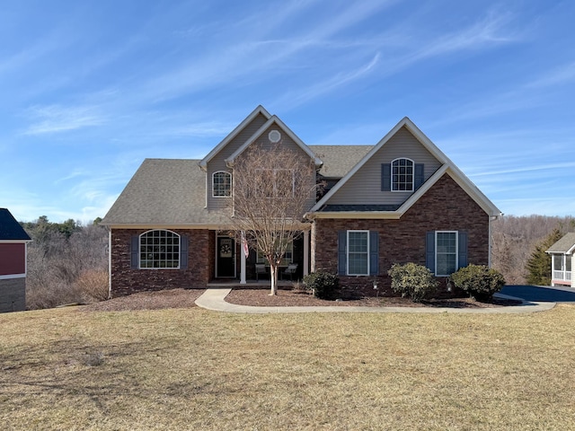 view of front of house with brick siding, a front lawn, and roof with shingles