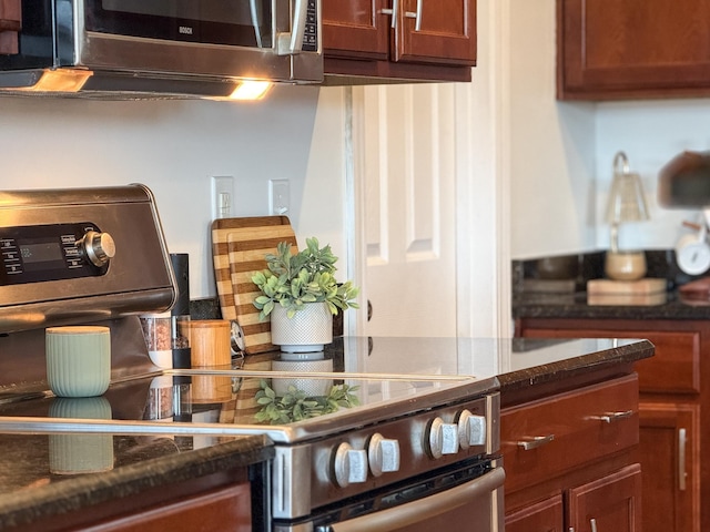 kitchen with dark stone counters, stainless steel microwave, and brown cabinets