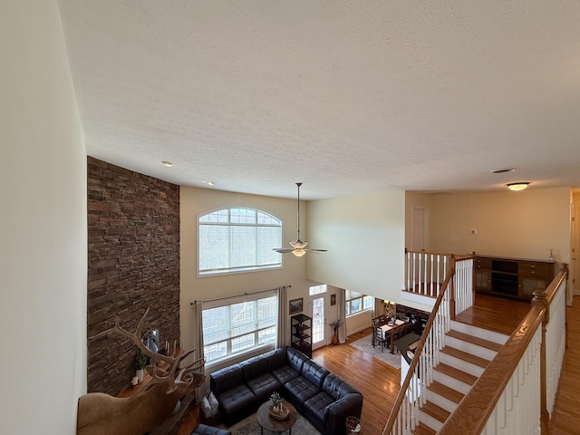 living area with a textured ceiling, a high ceiling, wood finished floors, and a ceiling fan