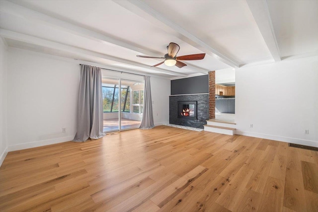 unfurnished living room featuring ceiling fan, light wood-style floors, baseboards, a brick fireplace, and beam ceiling