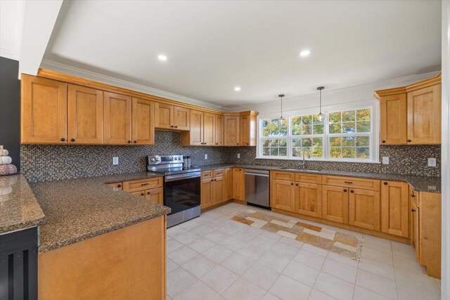 kitchen featuring brown cabinets, stainless steel appliances, crown molding, pendant lighting, and a sink