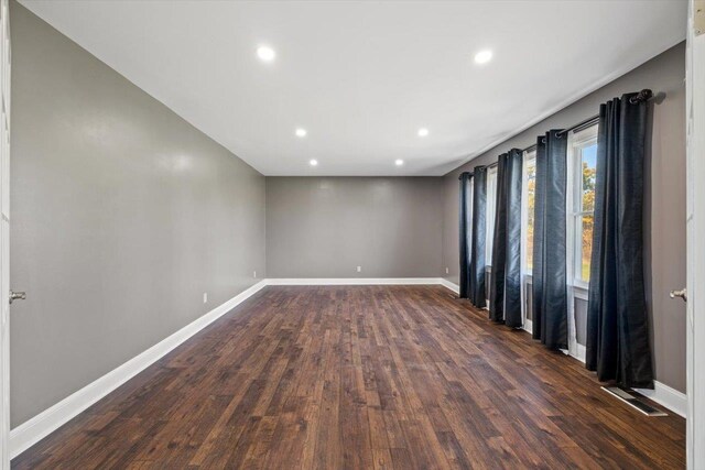 empty room with dark wood-type flooring, recessed lighting, visible vents, and baseboards