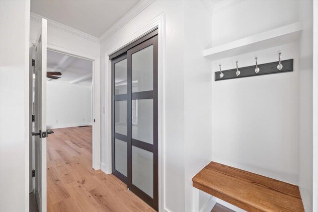 mudroom featuring light wood-type flooring, crown molding, and baseboards