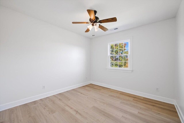 empty room with a ceiling fan, visible vents, light wood-style flooring, and baseboards